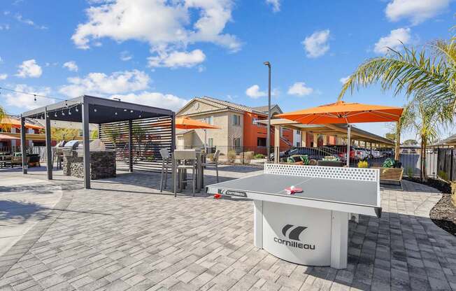 A white table tennis table with the brand name "Camilleau" on it is placed on a patio.