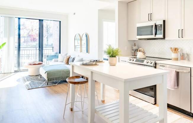 a white kitchen with a white island and a living room