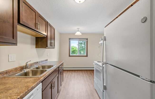 a kitchen with a sink and refrigerator and a window