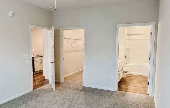 A room with a ceiling fan and three open doors.
