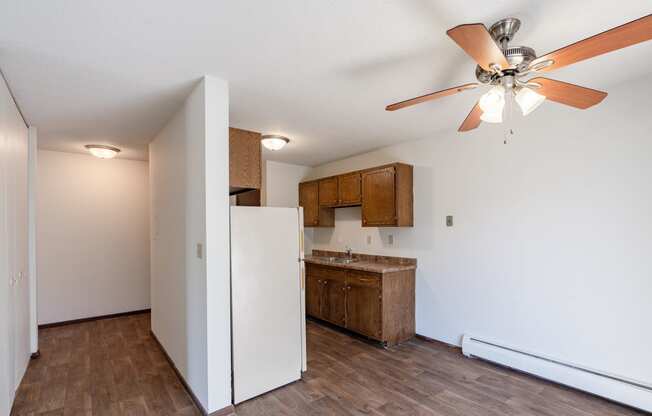 an empty kitchen with a ceiling fan and a refrigerator. Eagan, MN Glen Pond Apartments