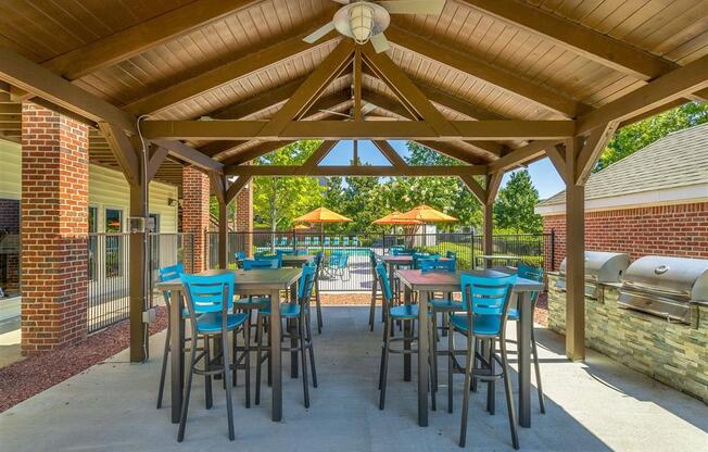 a patio with tables and chairs and a grill