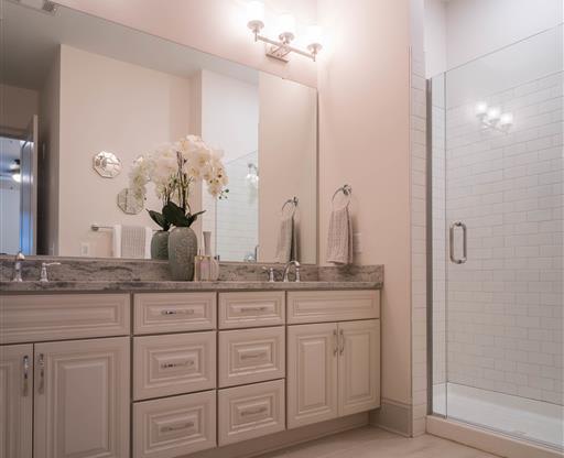 A spacious bathroom with a dual-sink vanity and a glass-enclosed shower.