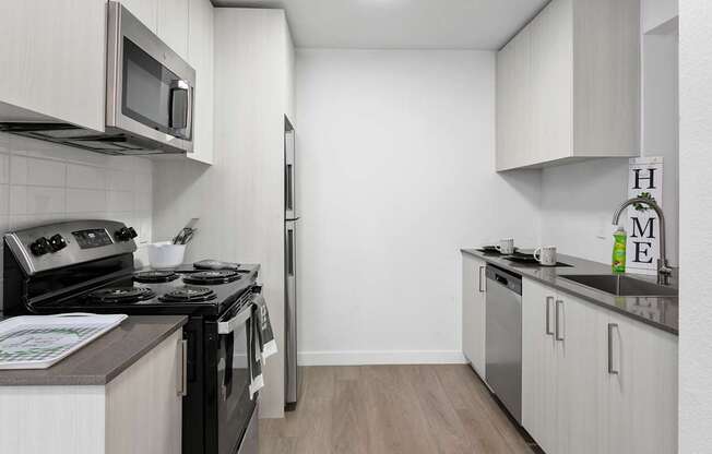 A kitchen with a black stove top oven and a microwave above it.