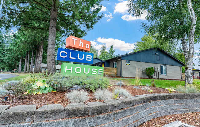 A sign that says The Club House is in front of a building.