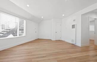 a living room with white walls and a large window and wooden floors