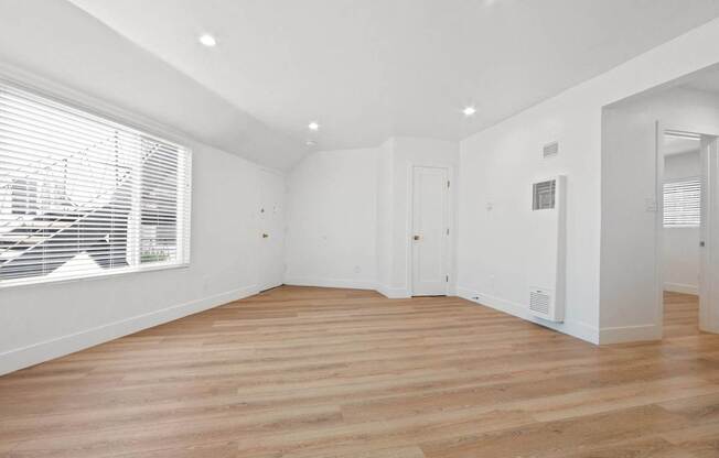 a living room with white walls and a large window and wooden floors