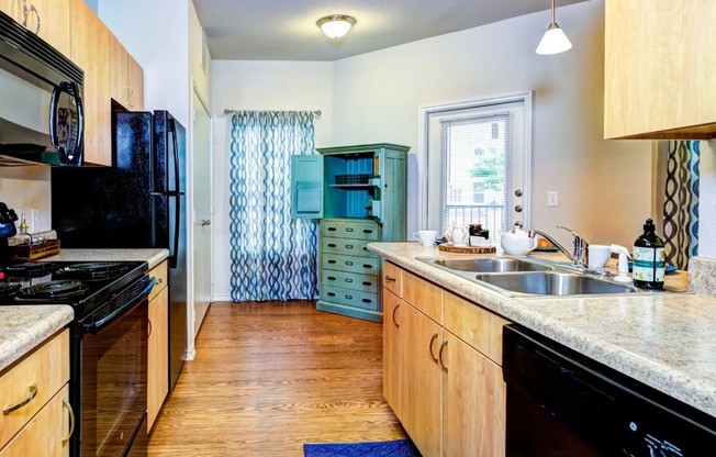 a kitchen with a black stove top oven next to a sink and a refrigerator at Villa Espada Apartments, Texas, 78221