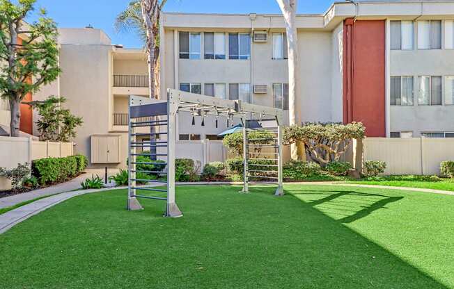 A playground with a slide and swings in front of a building.