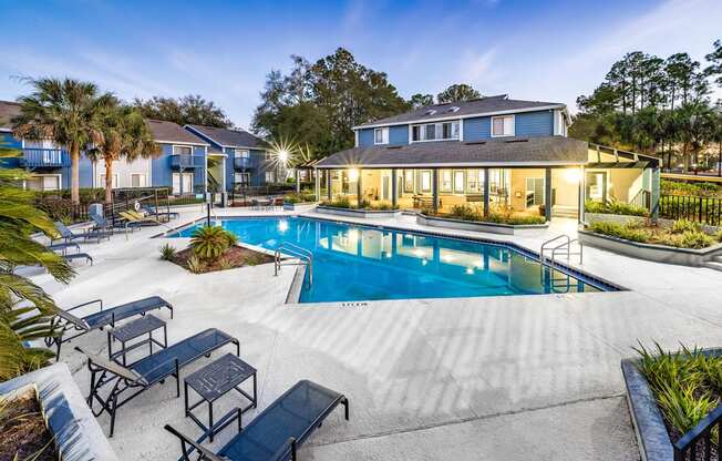 A swimming pool surrounded by a concrete patio and lounge chairs.