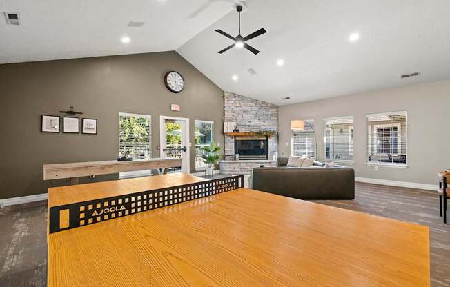 A large wooden ping pong table in the Clackamas Trails Clubhouse with a fireplace and a clock on the wall at Clackamas Trails Apartments, Oregon, 97222