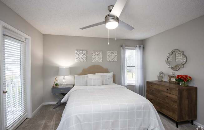 A bedroom with a bed, nightstand, and a dresser.