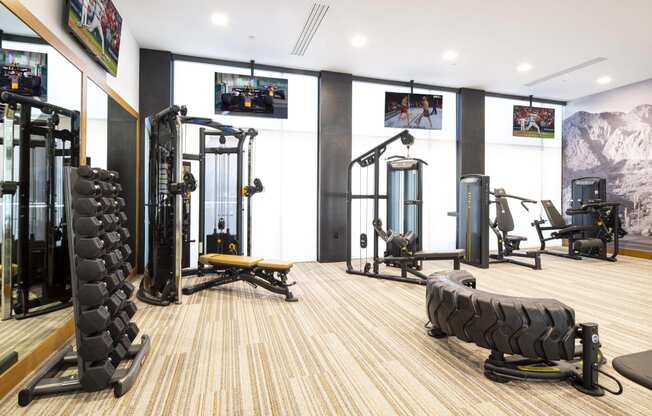 a gym with weights and cardio equipment on the floor and a wall of windows