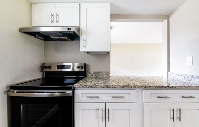 a kitchen with white cabinets and black appliances and granite counter tops at Palm Cove Apartments, Daytona Beach Florida