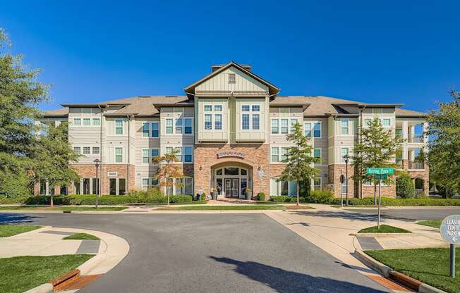 A large, modern building with a stone facade and a green lawn in front.