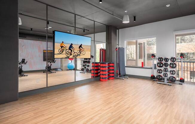 A gym with a large screen showing a cycling workout.