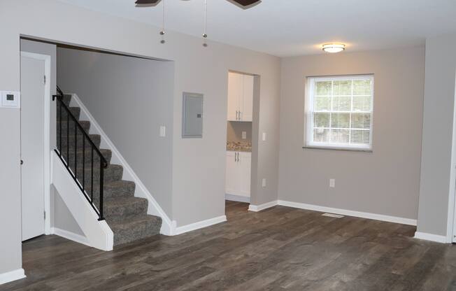 an empty living room with a staircase and a window