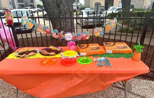 A table with an orange tablecloth is set up for an event.