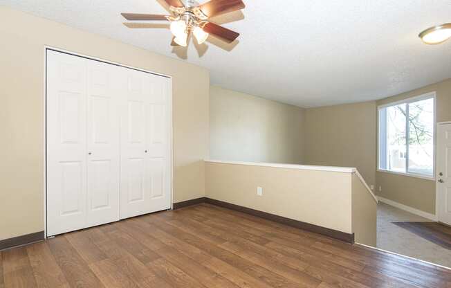 an empty living room with wood floors and a ceiling fan