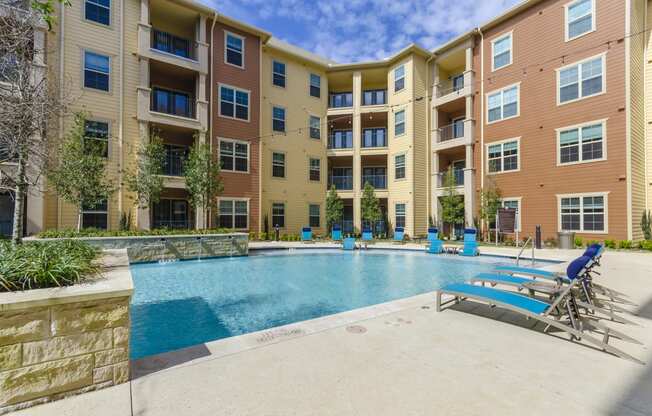 an apartment building with a swimming pool and lounge chairs