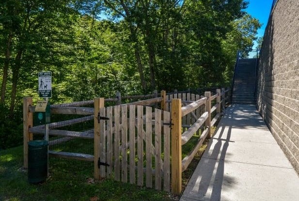 A wooden fence and gate lead to a pathway in a park.
