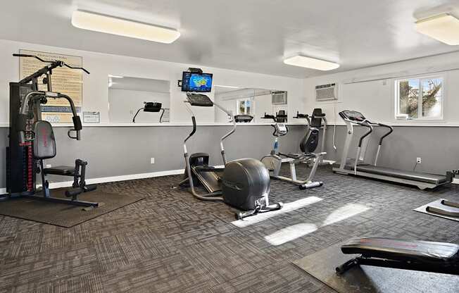 a gym with exercise machines and a tv on the wall