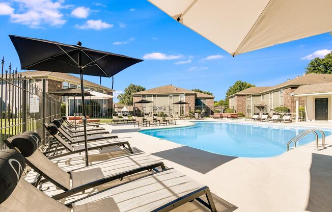 Tanning chairs and umbrellas in poolside lounge area at The Arbor in Blue Springs, Missouri