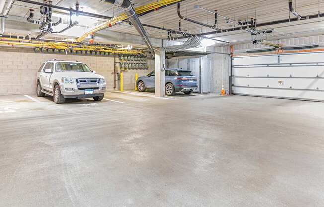 A white SUV is parked in a garage with a blue car behind it.