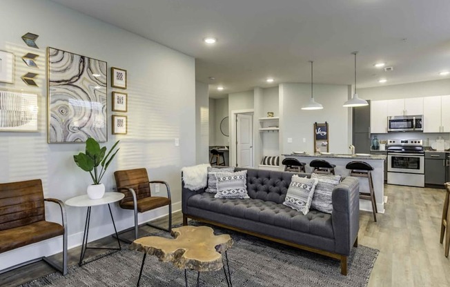 a living room with a couch and a kitchen in the background at Echo Park at Perry Crossing Apartments, Indiana, 46168