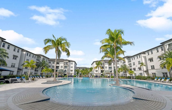 Palm trees flanking either side of the pool in the center of the apartment home buildings