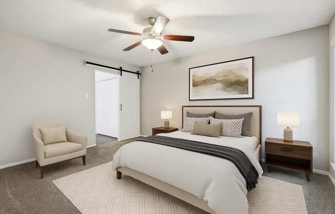 A bedroom with a large bed, a chair, and a ceiling fan.