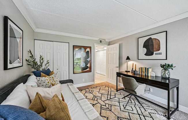 A living room with a black and white patterned rug, a white sofa, a black coffee table, and a framed picture on the wall.