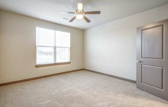 an empty room with a ceiling fan and a window