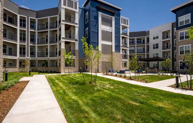 an exterior view of an apartment building with green grass and a sidewalk