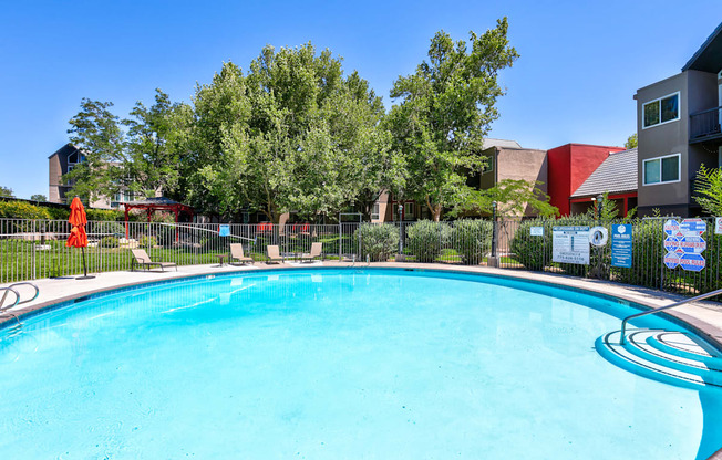A swimming pool surrounded by trees and chairs.