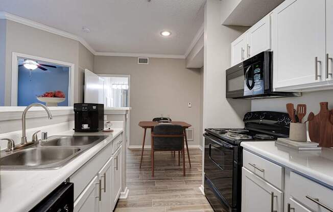 A kitchen with white cabinets and a black stove top oven.