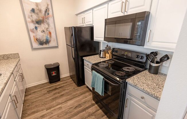 a kitchen with white cabinets and black appliances