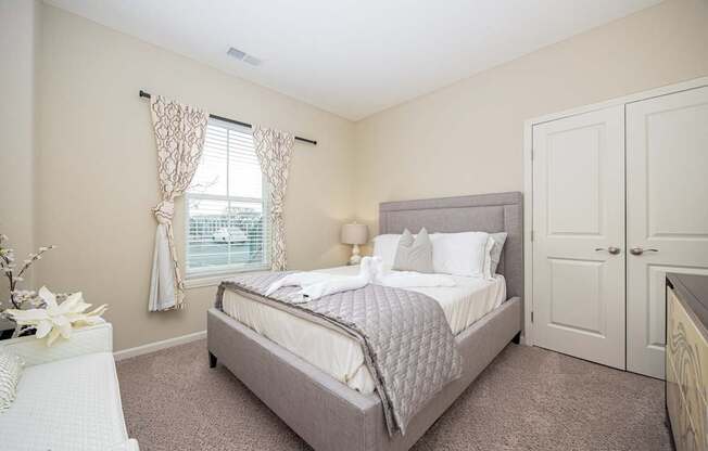 A bedroom with a bed, nightstand, and window.