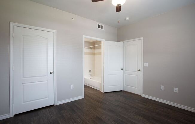 A room with a ceiling fan and three doors.