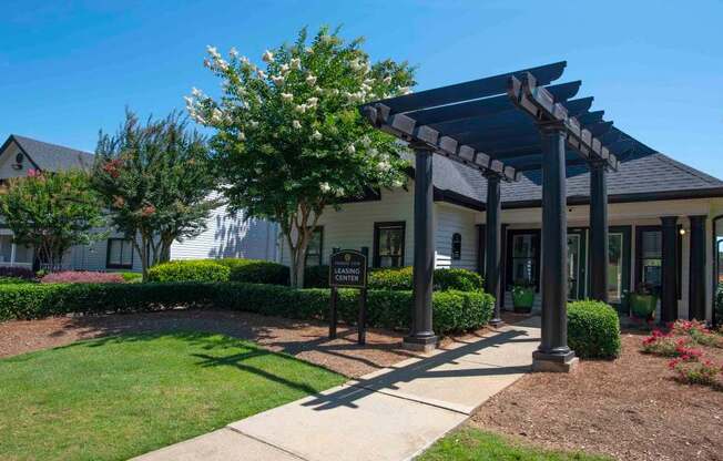 A building with a covered walkway entrance surrounded by greenery.