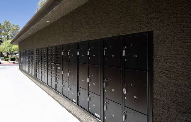 A row of black mailboxes are mounted on a wall.