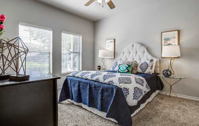 A bedroom with a bed, a dresser, and a ceiling fan.