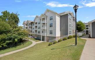 an apartment building on a sidewalk next to a grass field