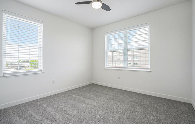 a bedroom with two windows and a ceiling fan at Meadowbrooke Apartment Homes, Michigan