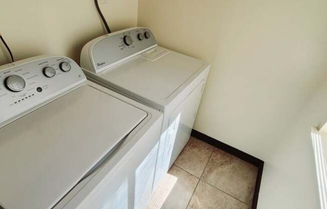 A white dryer and washer are stacked in a small laundry room.