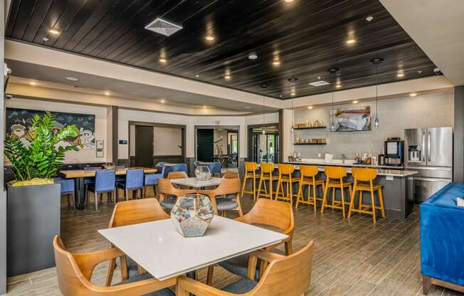 a dining area with tables and chairs and a kitchen in the background