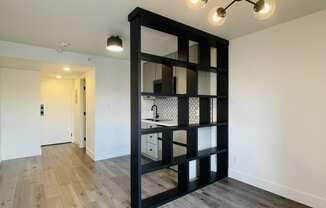 a black shelving unit in the center of a living room with wood flooring