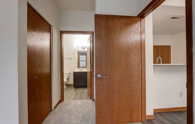 a bedroom with a closet and a bathroom with a sink and a mirror