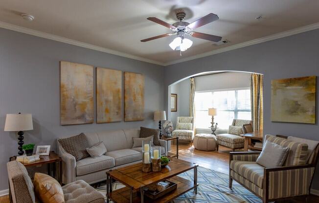 a living room with couches and a ceiling fan