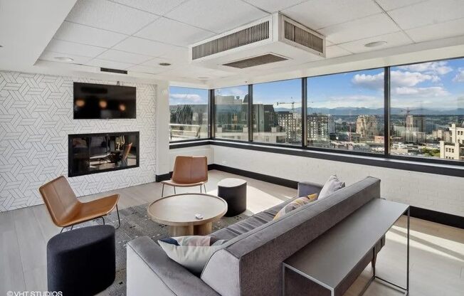 A living room with a grey couch, a coffee table, and a television at Archer Tower in Denver, CO